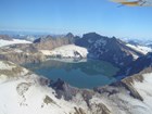 aerial view of a crater lake in a snowy, mountainous landscape
