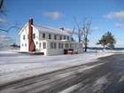 Two story Sleeping Bear Inn along a road in a bright snowy landscape beside Lake Michigan