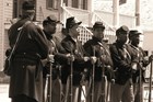 Sepia tone photo shows six Black men dressed as African American soldiers.