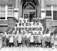 Black and white photo shows Black students and teachers standing on stairs.
