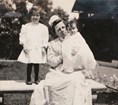 A woman sitting outside with two small children
