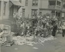 Black and white photo of group of kids with scraps and piles of paper