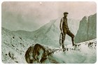 a person standing on glacier ice with a rope and mountains behind