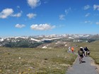 People hike along a paved trail in the mountain tundra.