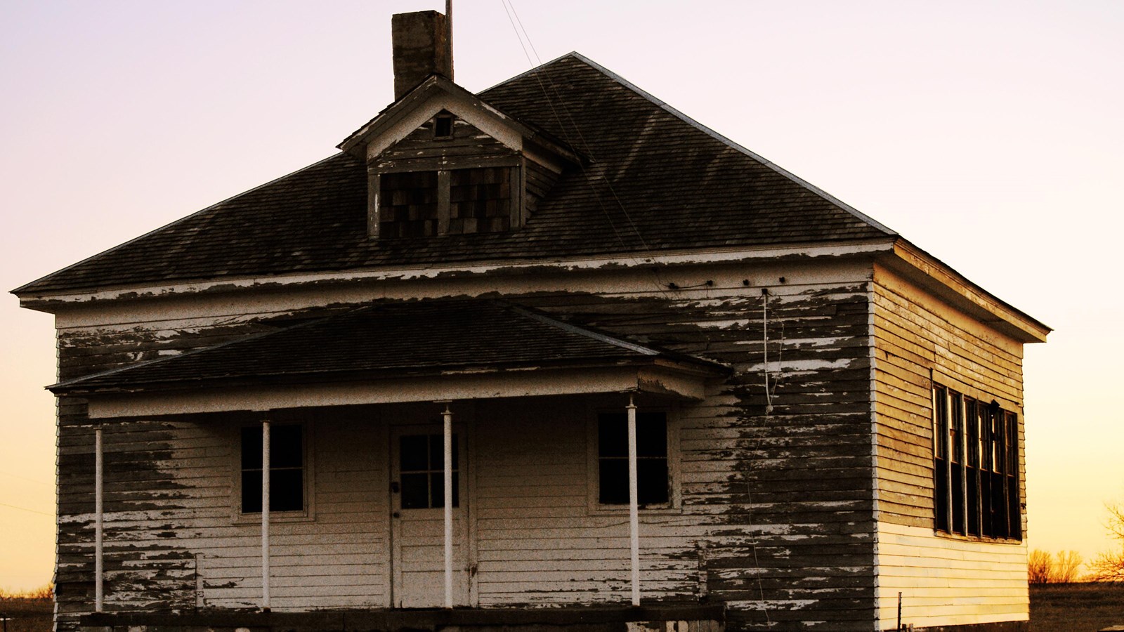 A wooden schoolhouse with chipped white paint