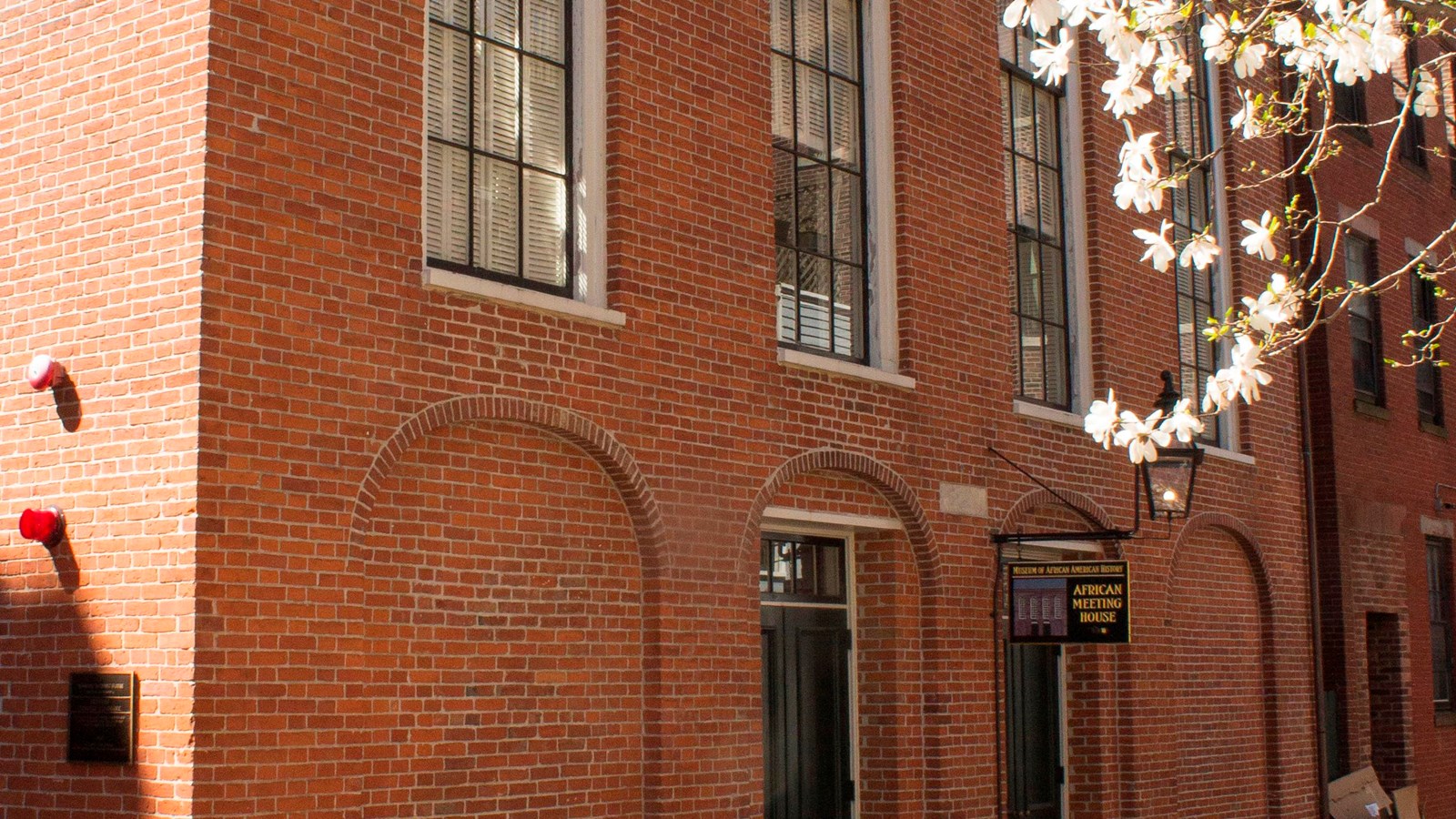 A brick two story-building with large vertical rectangular windows rounded at the top.