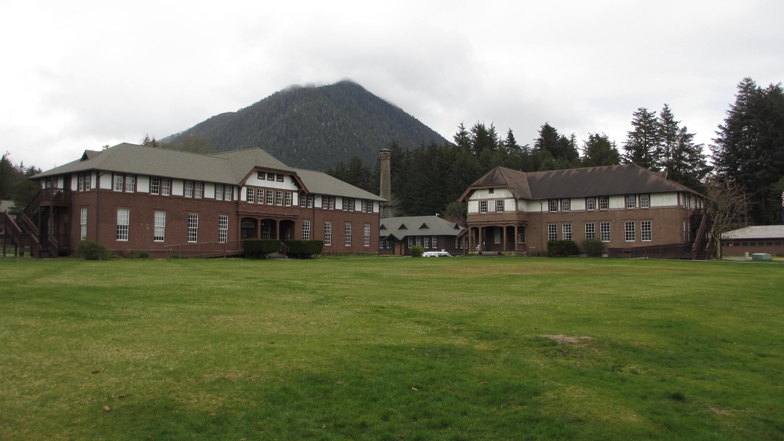 Two brown and white Craftsmen-style two story building in front of a grassy quad.