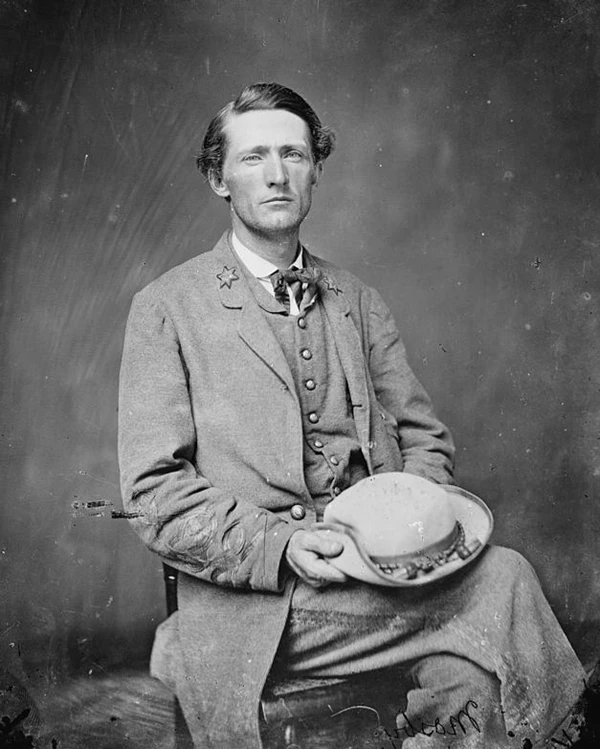 Mosby, wearing his Confederate officer's uniform, seated in a chair holding a hat in his lap.