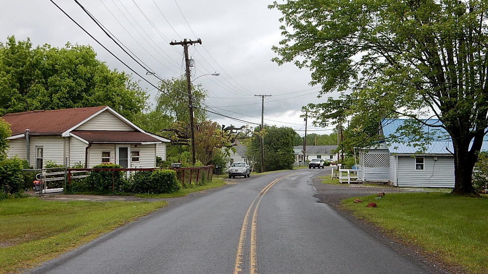 Looking up the middle of a street with small houses on either side of the road.