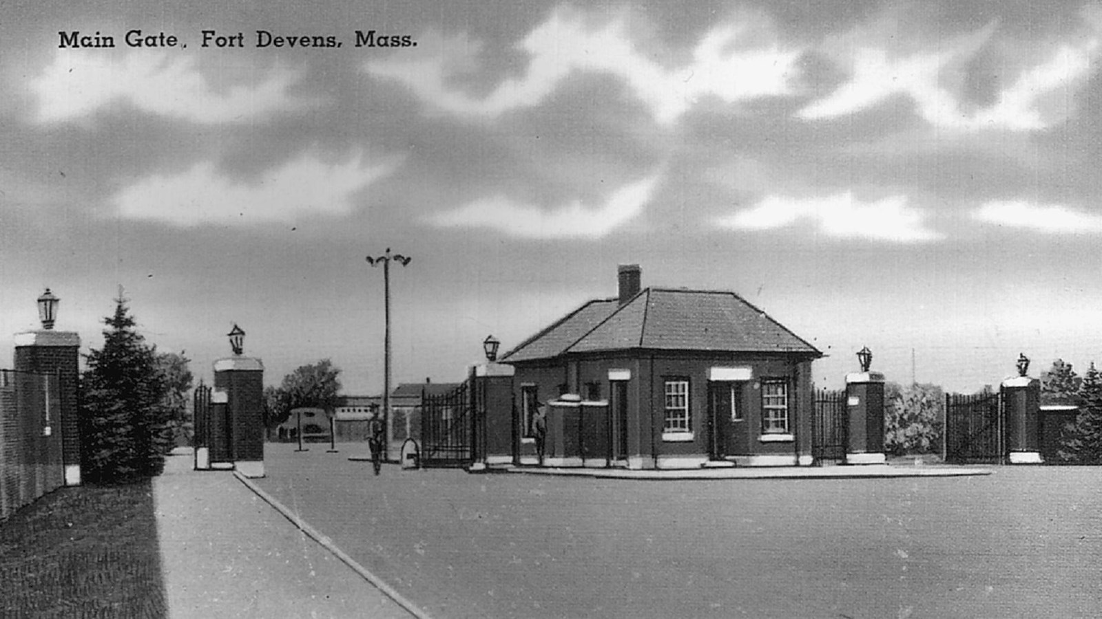 Black and white photoillustration of low brick buildings and gate with text 