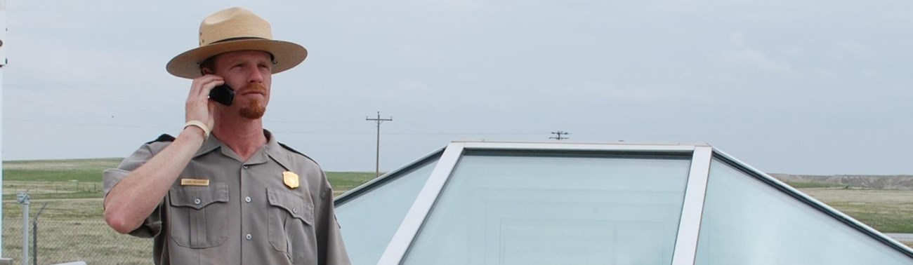 A park ranger stands in front of a glass enclosure at a missile silo