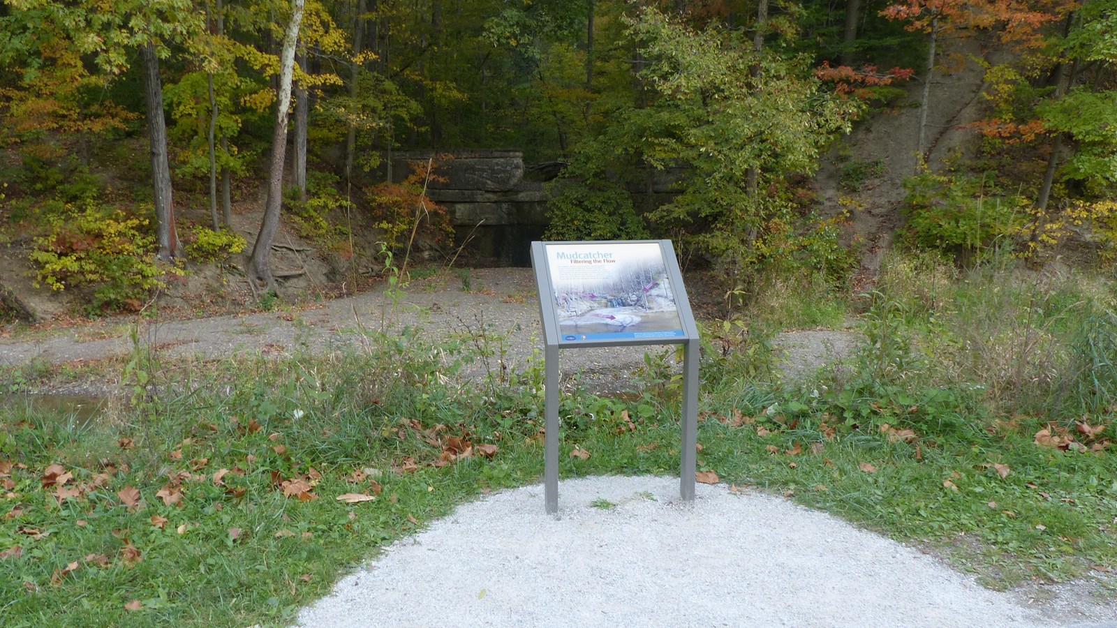 In a half circle bump out, a square graphic panel overlooks a canal choked with soil. On the opposit