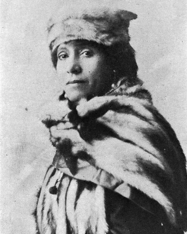 Black and white photo of a woman with a fur cap and cloak around her shoulders.