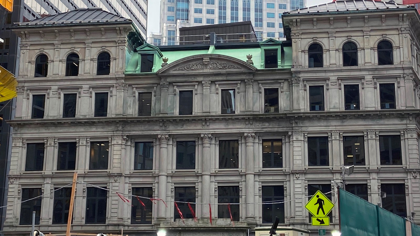 5-story grey stone building with rectangular windows. The 5th story facade is arched in the center.