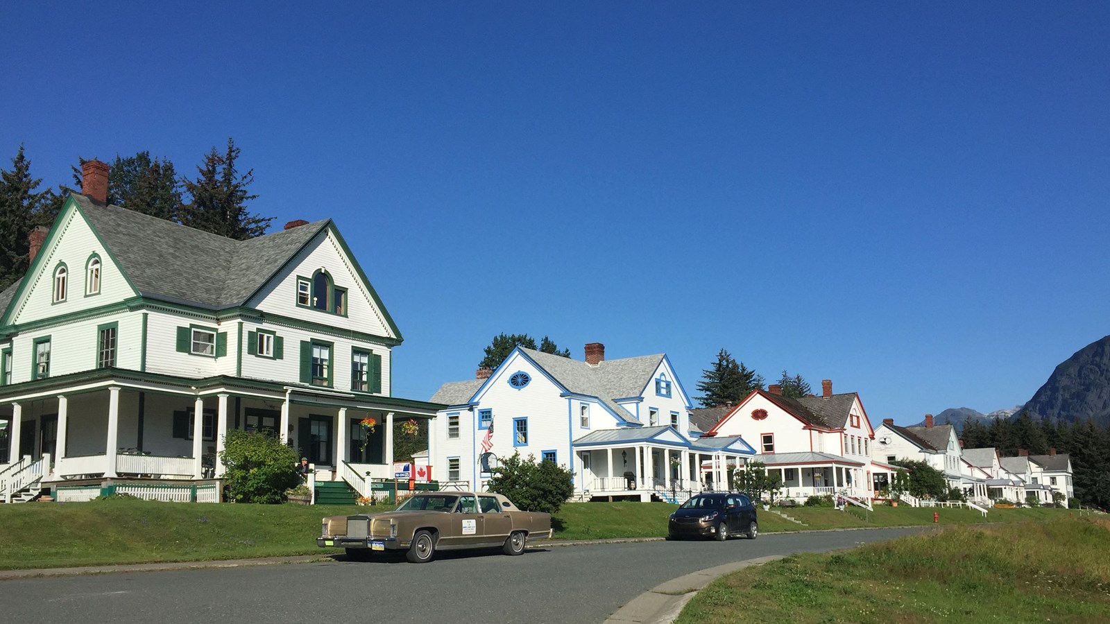 A row of three story white homes with colorful painted trims