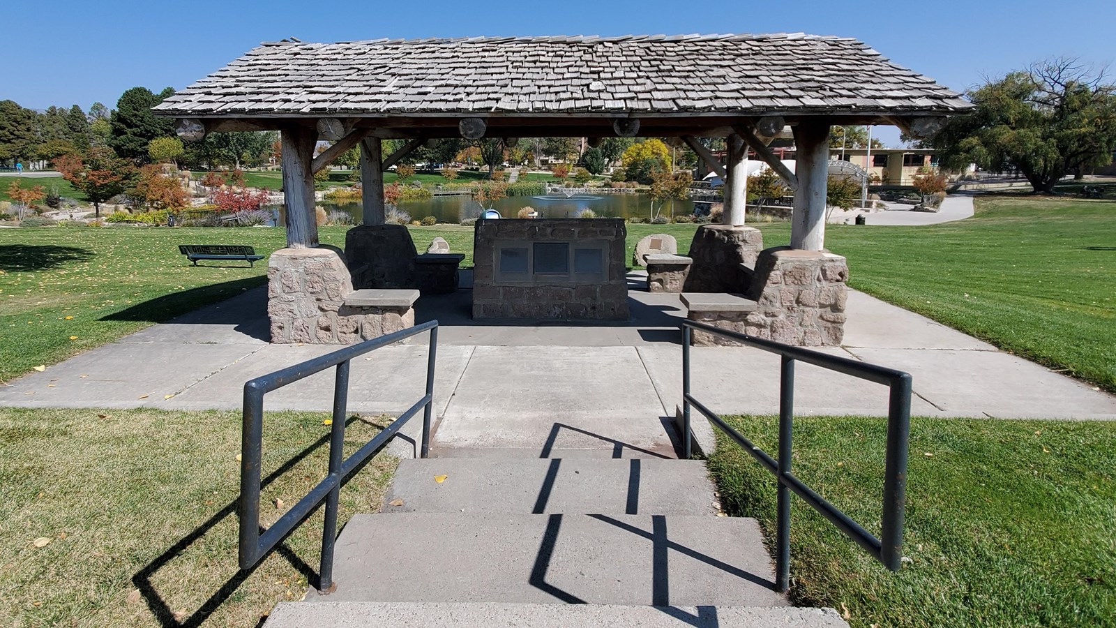 A shingle roof sits atop stone corner posts, surrounded by a grassy lawn