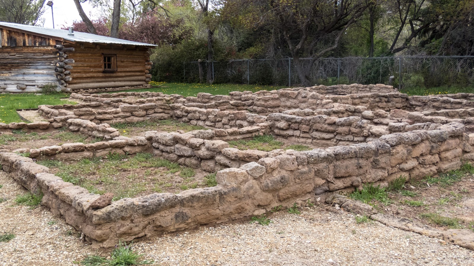 Short stone walls form the shapes of rooms on a grassy lawn.