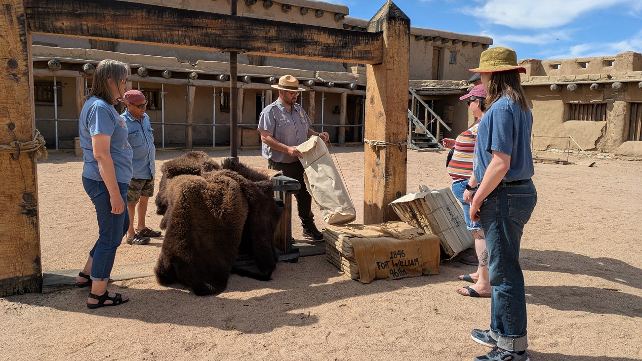 A park ranger explains the wooden fur press inside the fort to a small group of visitors. 