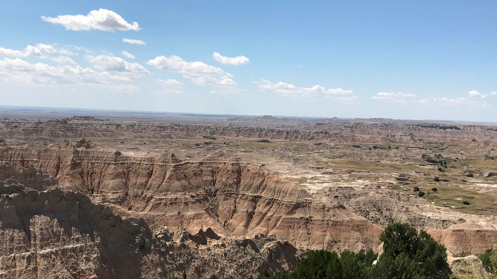 A dramatic Badlands landscape consisting of layered, jagged rock extending into prairie landscape.