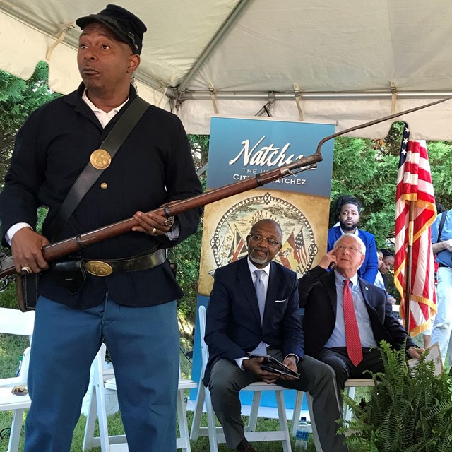 A man dressed as a Union soldier stands holding a rifle