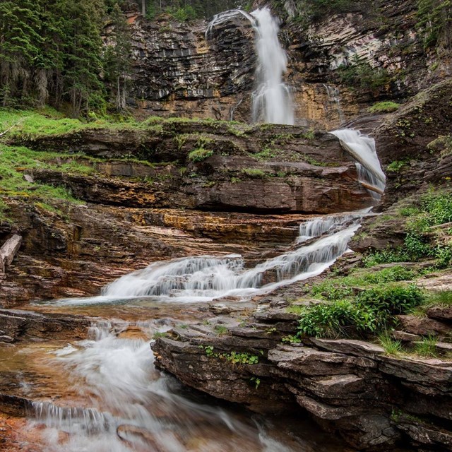 Water cascading down multiple levels of a plant-lined waterfall