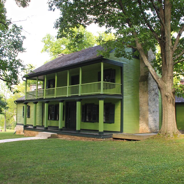 Two-story green house in a large yard