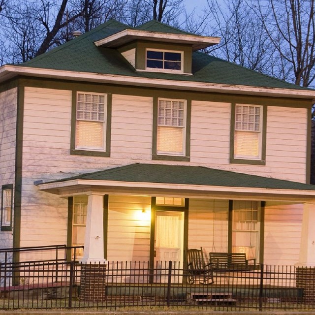 Two-story white house with a green roof