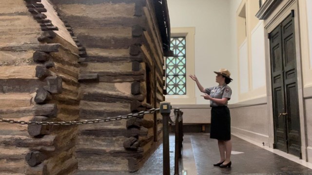 Ranger pointing at log cabin