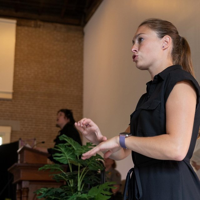 photo of woman signing with her hands in front of a crowd.