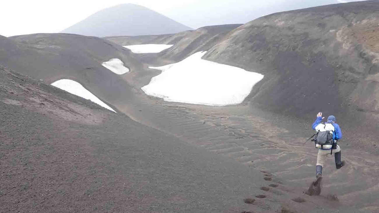 A man bounds down volcanic dunes.