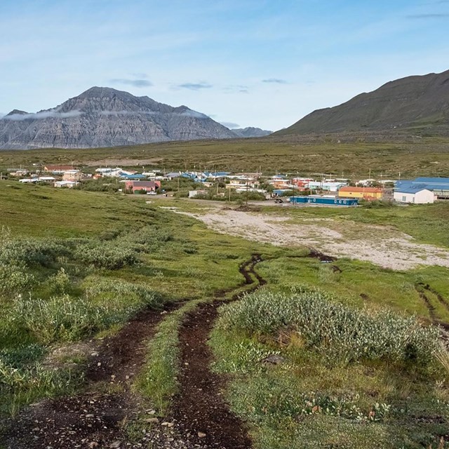 An image of a village from the sky. There are mountains in the background.