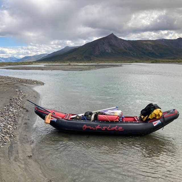 A raft sits on the bank of of river.