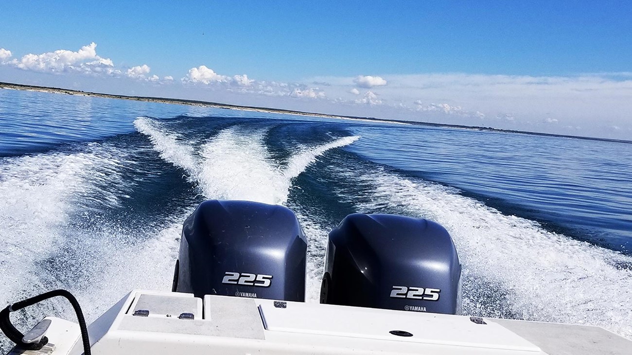 Motorboat stern making a sharp turn and wakes on a still, blue lake