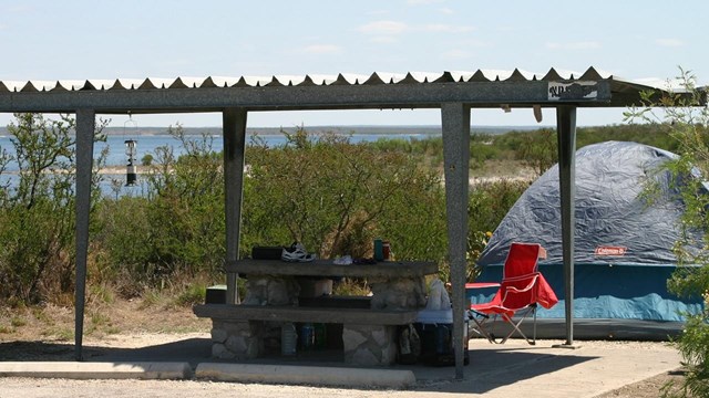 Picnic shelter with table and tent in a Governors Landing campsite.