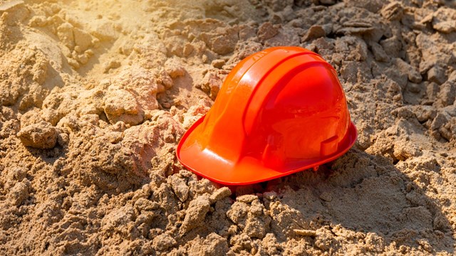 Photograph of orange hard hat in sand. 