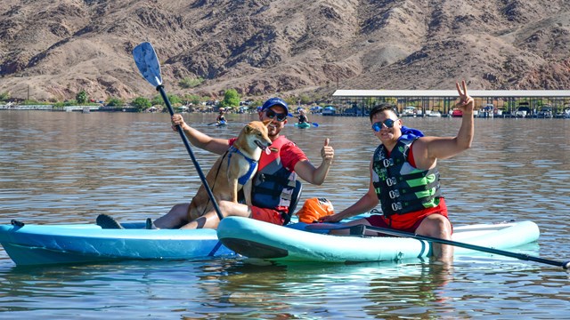 Two people smile on a standup paddleboard.