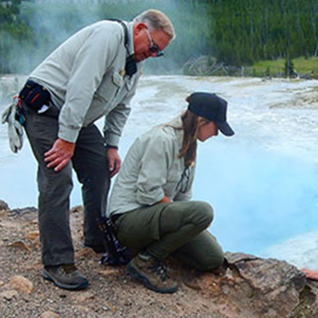 Megan and two others look at rocks eroding from a shoreline