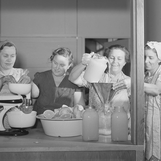 A group of women work in a community kitchen to preserve fruits