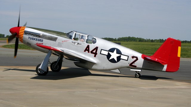 A silver plane with a red tail and elevator