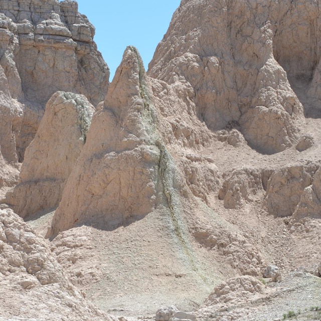 a green vertical line runs through a brown badlands peak