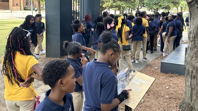 A group of students standing between metal statues learning about the Civil Rights Movement.