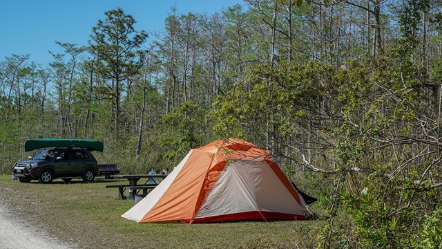 A tent in front of a car with a canoe on top