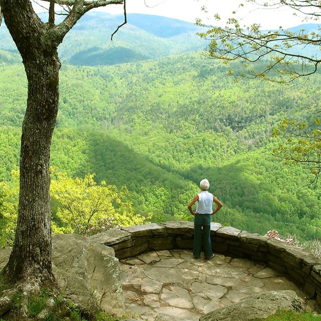 A woman stands on a flagstone patio overlooking a view of the mountains