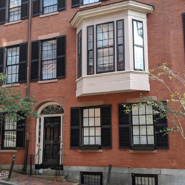 Brick residential building with a white bay window on the second floor