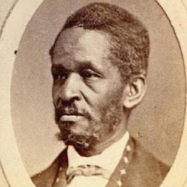 Side profile of African American Lewis Hayden, with cropped hair, long sideburns, and goatee.