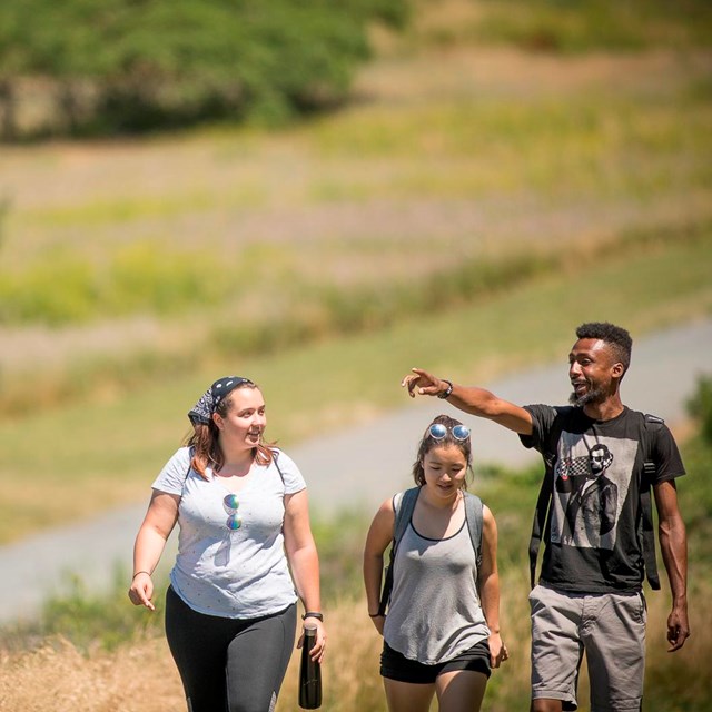 Three walkers (one man and two women) on a trail at Spectacle Island.