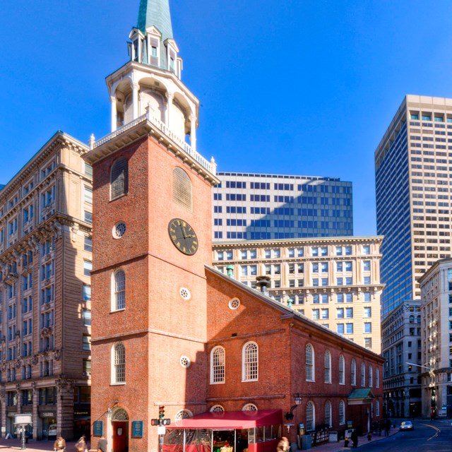 Brick two story building with a brick steeple in the center-front of the building.