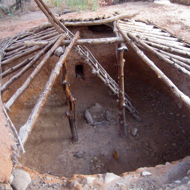 Looking down through beams into a partially exposed pit house