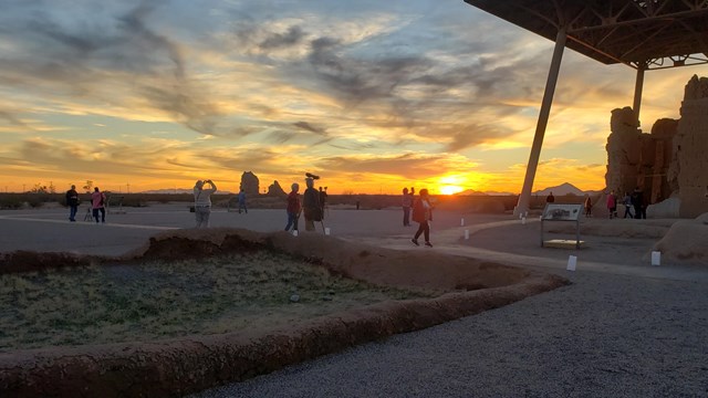 A family poses for a picture in front of a large adobe structure. 