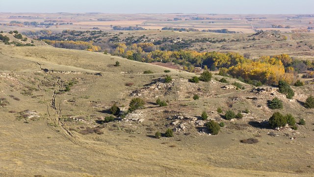 A large sweeping hill leads out onto a landscape of canyons in a desert setting.